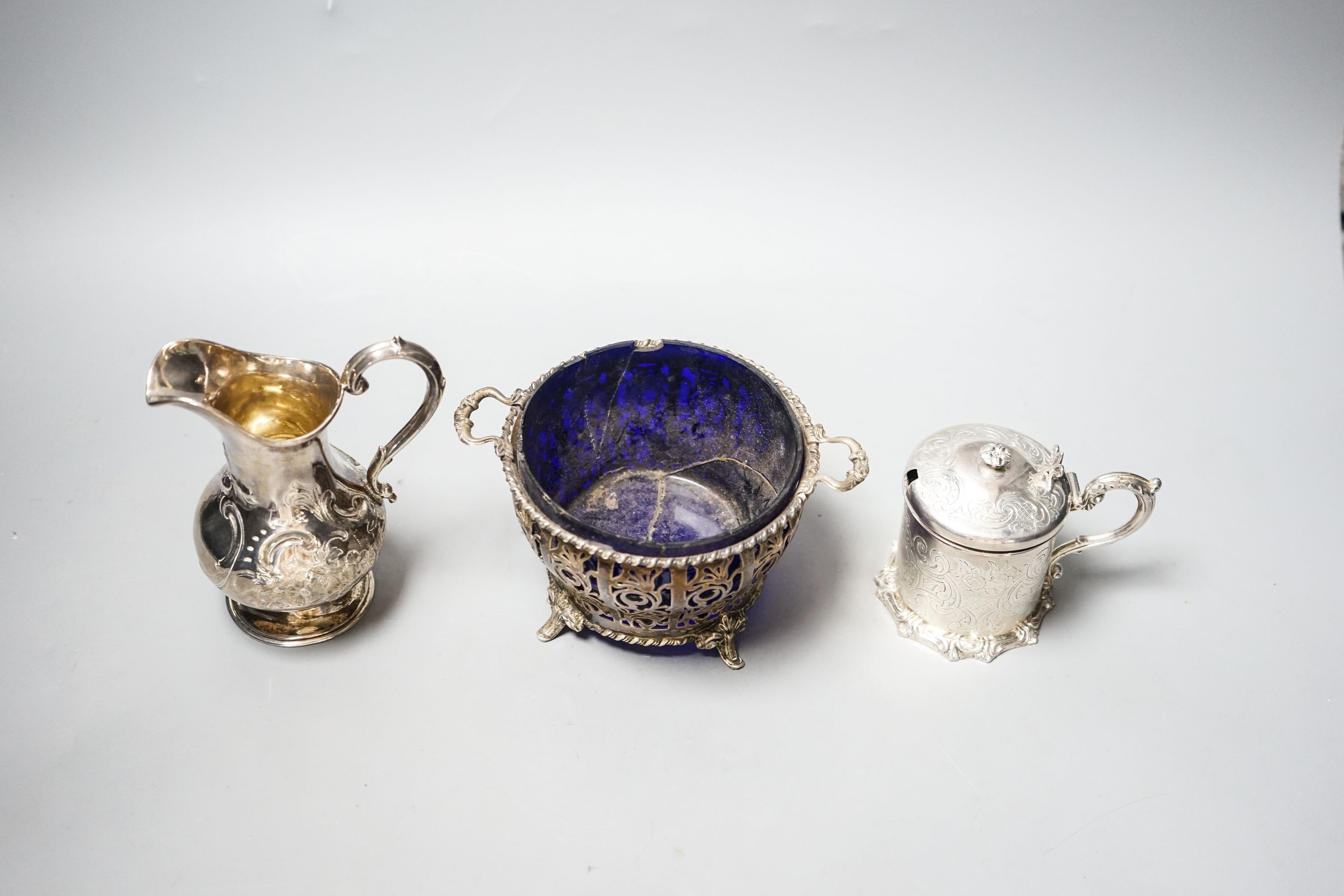 A Victorian silver cream jug, London, 1851, a Victorian silver mustard and a 1930's pierced silver two handled bowl, with blue glass liner.